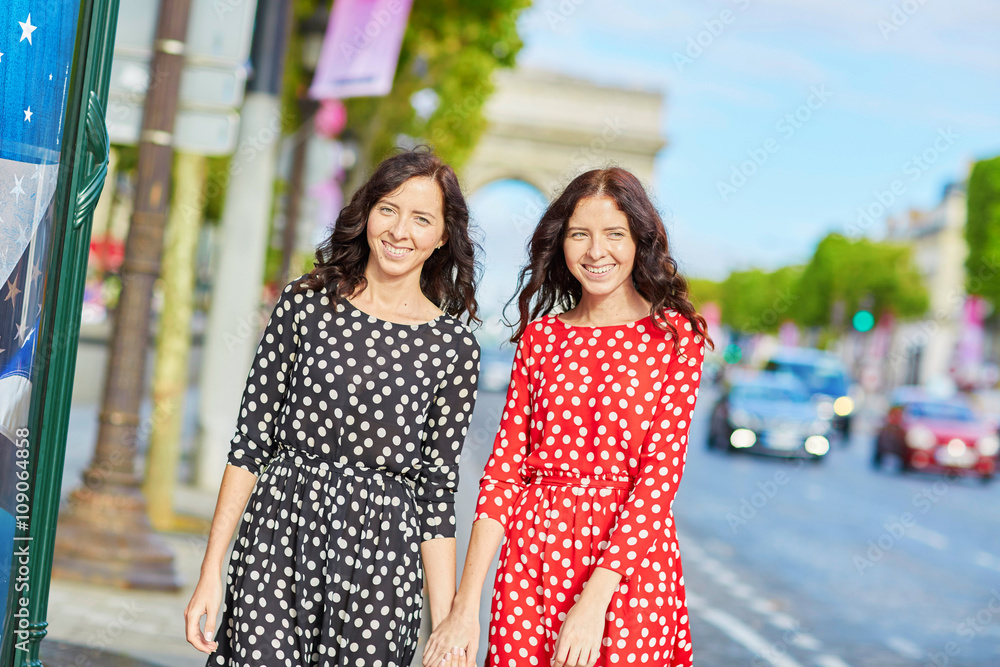 Naklejka premium Beautiful twin sisters in front of Arc de Triomphe