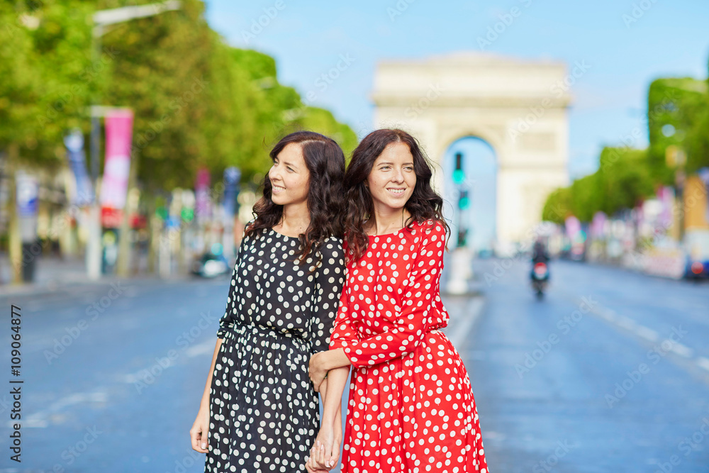 Beautiful twin sisters in front of Arc de Triomphe
