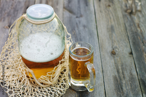 Fresh beer in a glass and in a glass jar on a wooden simple surface. Soviet still life with a glass jar of beer in a string-bag. photo