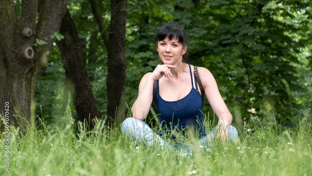Girl sits and smiles on background of grass Girl sits and smiles on background of grass