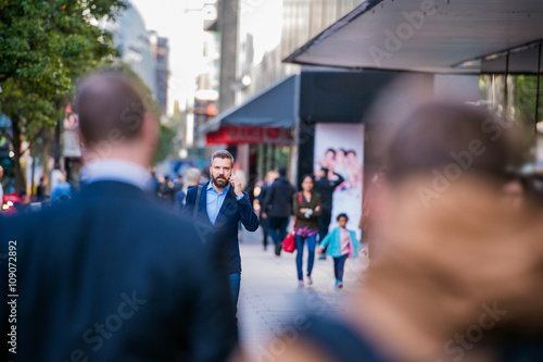 Hipster manager with smart phone walking in the street