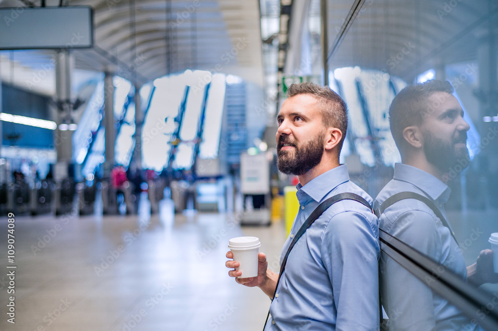 Hipster businessman holding a coffee cup, subway station Hipster businessman holding a coffee cup, subway station
