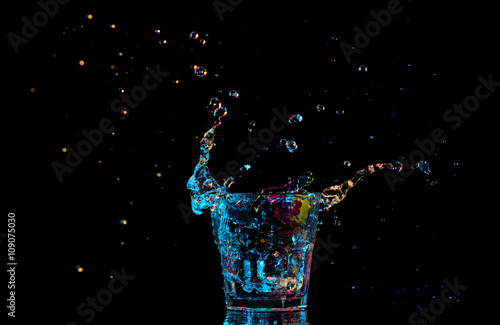 cocktail in glass with splashes on dark background. Party club entertainment. Mixed light.