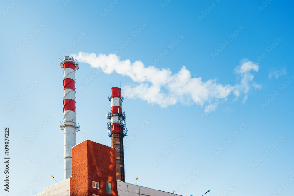 Boiler house chimney. Steam against the clear blue sky. Industrial zone of the city.