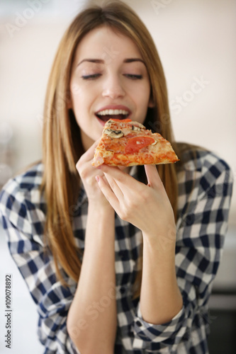Happy young woman eating slice of hot pizza  close up