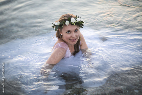 Beautiful Bride in a wedding-dress swimming in the water. Summer wedding on the beach. Honeymoon.