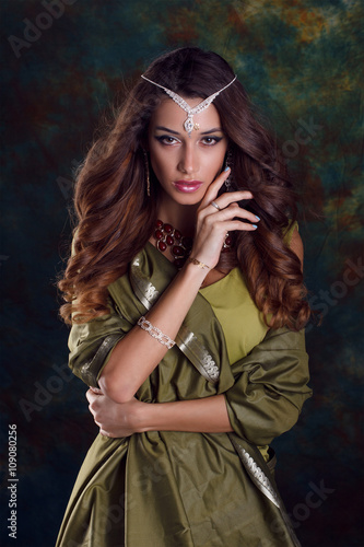 Beautiful woman in green indian sari and jewelry on colorful bac