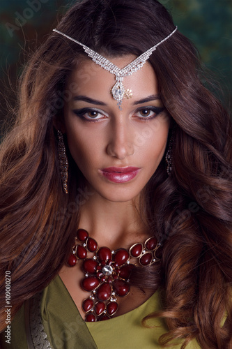 Beautiful woman in green indian sari and jewelry on colorful bac