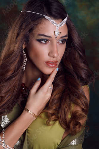 Beautiful woman in green indian sari and jewelry on colorful bac