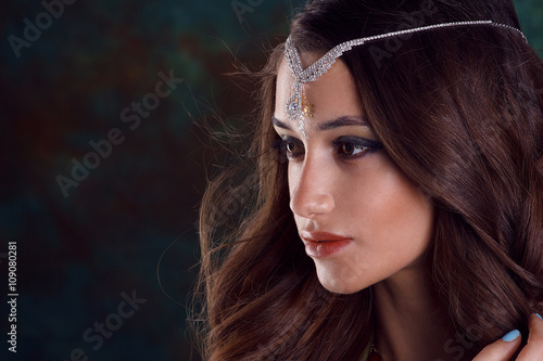 Beautiful woman in green indian sari and jewelry on colorful bac