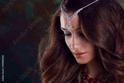 Beautiful woman in green indian sari and jewelry on colorful bac