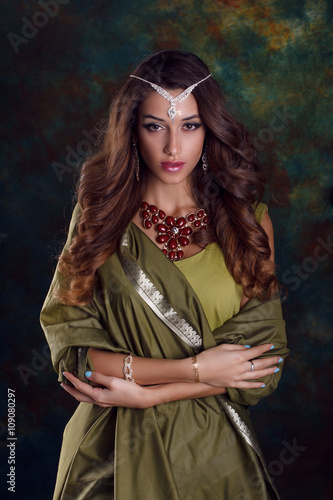 Beautiful woman in green indian sari and jewelry on colorful bac