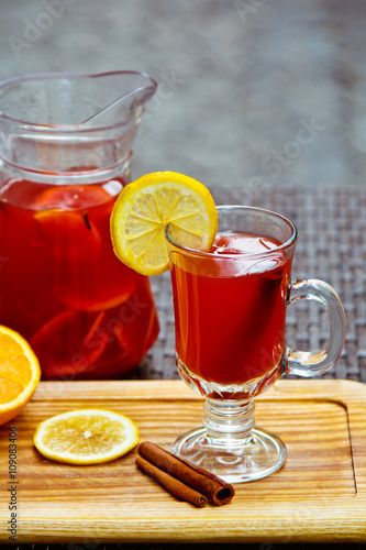 Refreshing summer fruit lemonade with orange and cinnamon in a beautiful glass and jar on wooden background