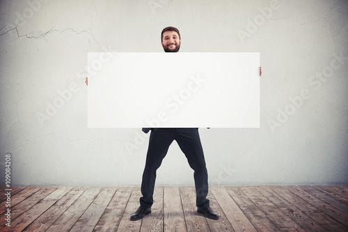 Businessman holding blank horizontal white banner. Place for tex
