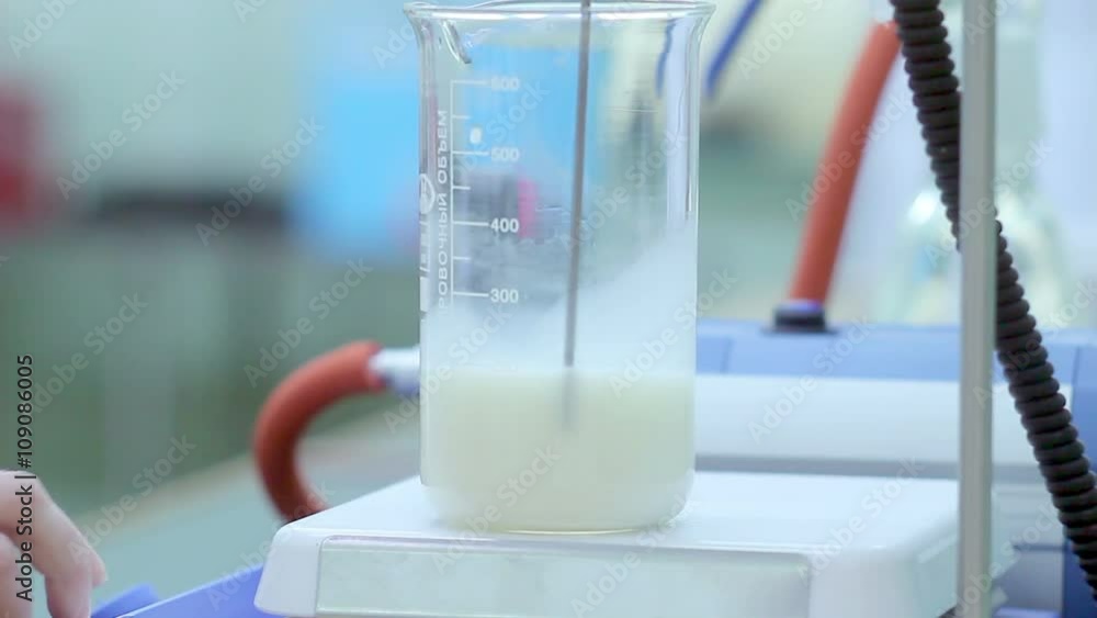 Analysis of milk. Laboratory scientist put measuring cup with liquid on
