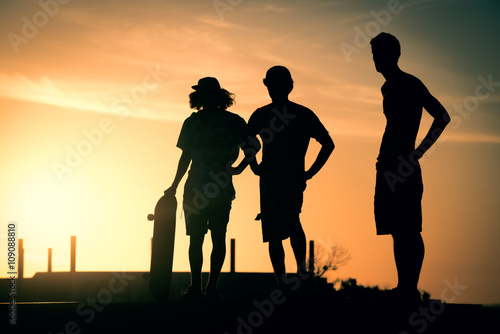 Teen boys silhouette at skate park on summer