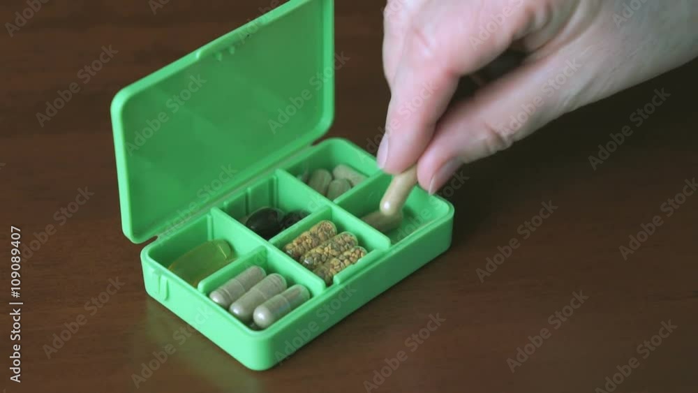 Woman's hand puts capsules tablets in container Woman's hand puts capsules tablets in container