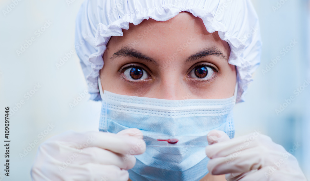 Closeup headshot nurse wearing bouffant cap and facial mask holding up blood sample on slide glass for camera Closeup headshot nurse wearing bouffant cap and facial mask holding up blood sample on slide glass for camera