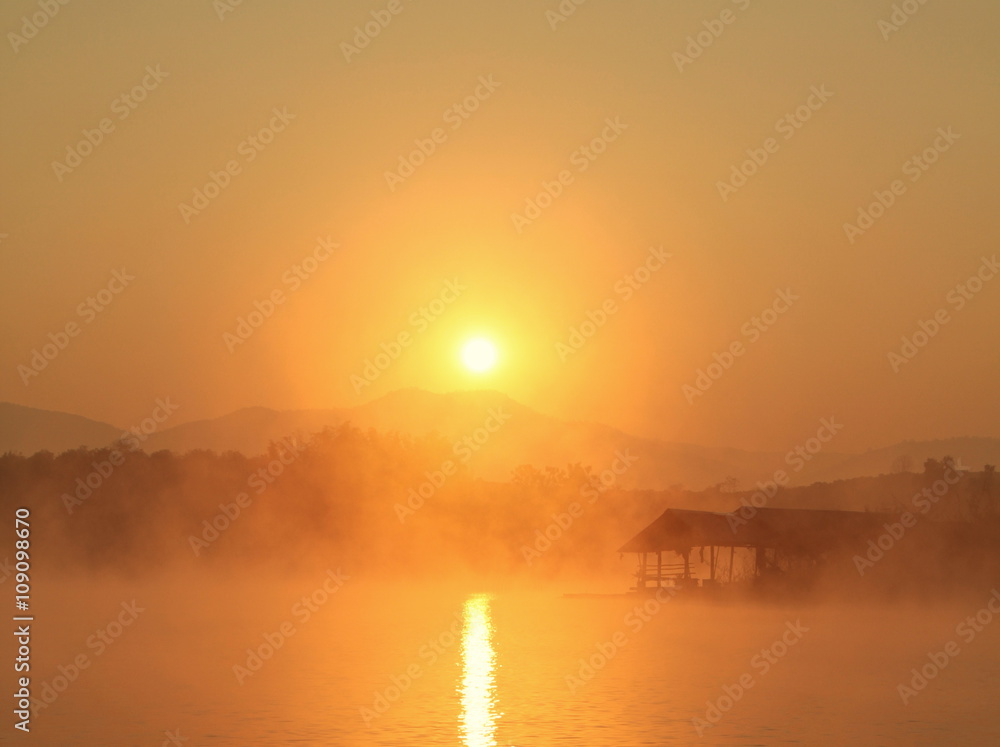 Misty tropical sunset on lake with wooden house in Mae Ngad Dam and Reservoir, Chiang Mai, Thailand