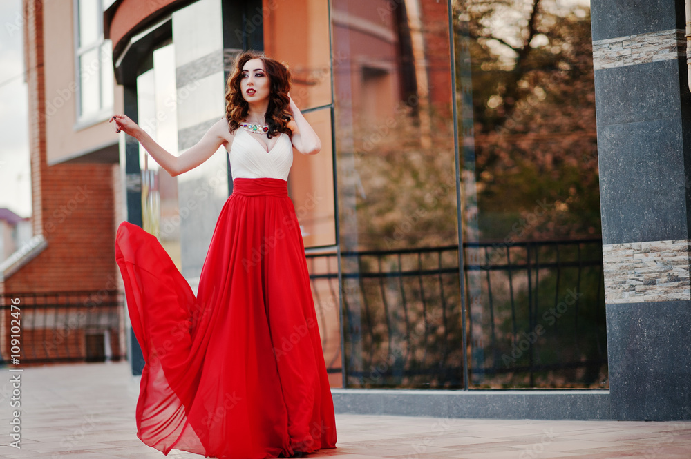 Obraz premium Portrait of fashionable girl at red evening dress posed backgrou