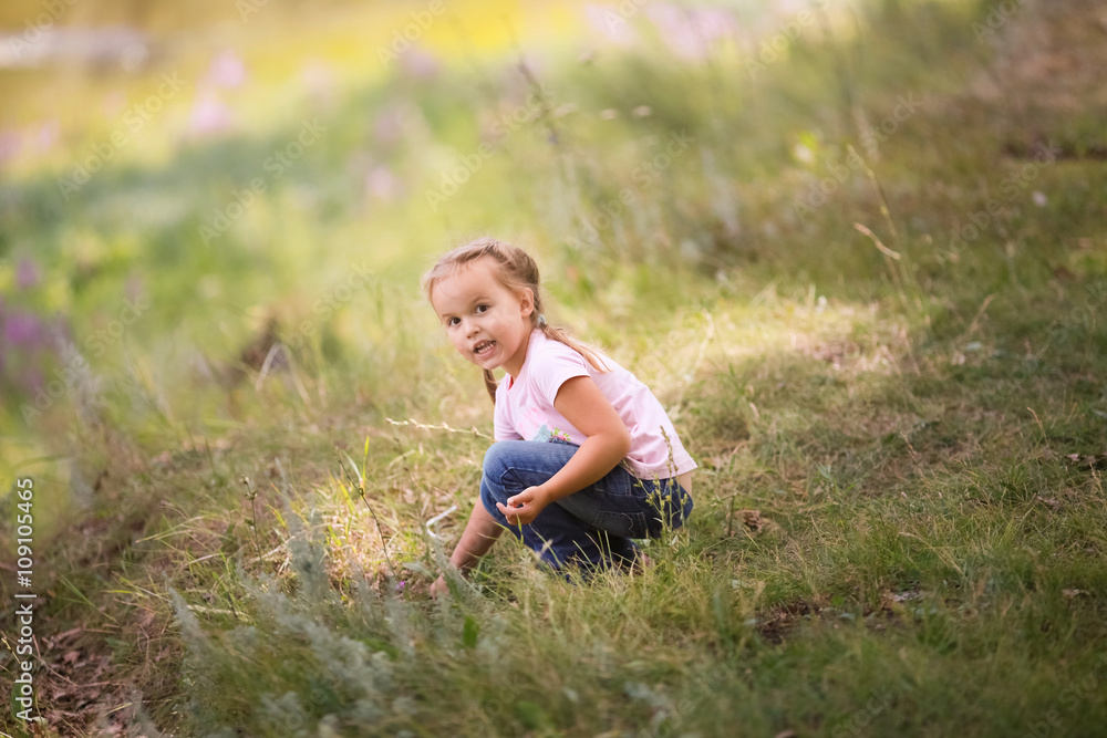 Five-year girl sitting in grass. In a pink t-shirt and jeans