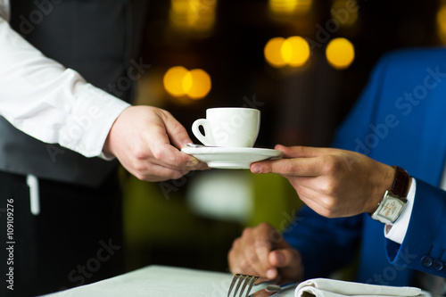 close-up of a waiter serves coffee young businessman in a restaurant