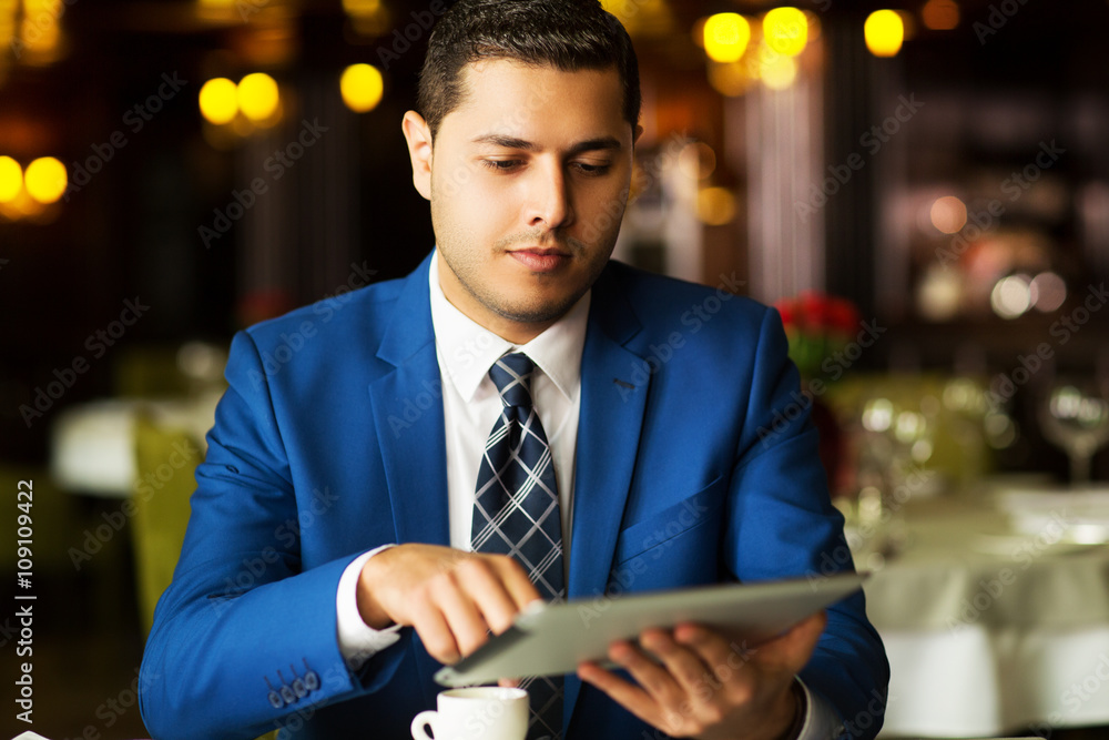 morning coffee, a young businessman with the tablet in a restaurant.young handsome businessman drinking coffee in a restaurant morning coffee, a young businessman with the tablet in a restaurant.young handsome businessman drinking coffee in a restaurant