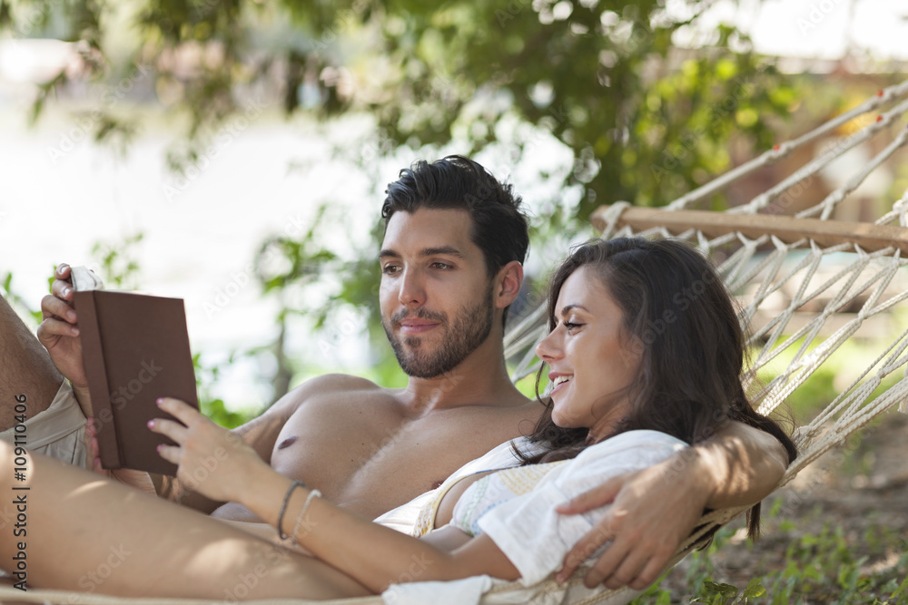 happy couple in love reading a book in hammock,selective focus happy couple in love reading a book in hammock,selective focus