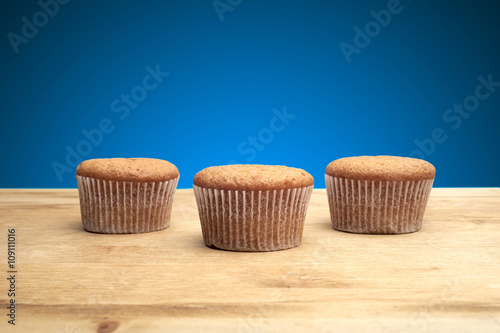 Fototapeta Naklejka Na Ścianę i Meble -  Three cupcakes on a wooden table