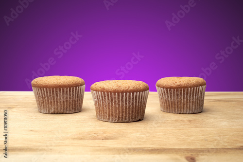 Fototapeta Naklejka Na Ścianę i Meble -  Three cupcakes on a wooden table