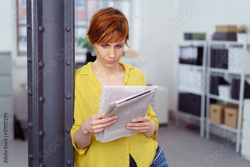 frau im büro liest die zeitung im stehen