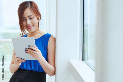 Smiling female business executive reading news on her tablet