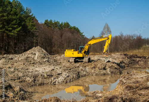 large yellow excavator Yellow on a construction site against blu sky