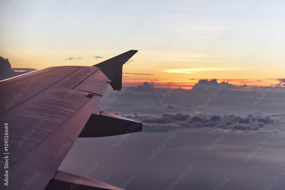 Obraz premium flying aircraft wing on beautiful sunset