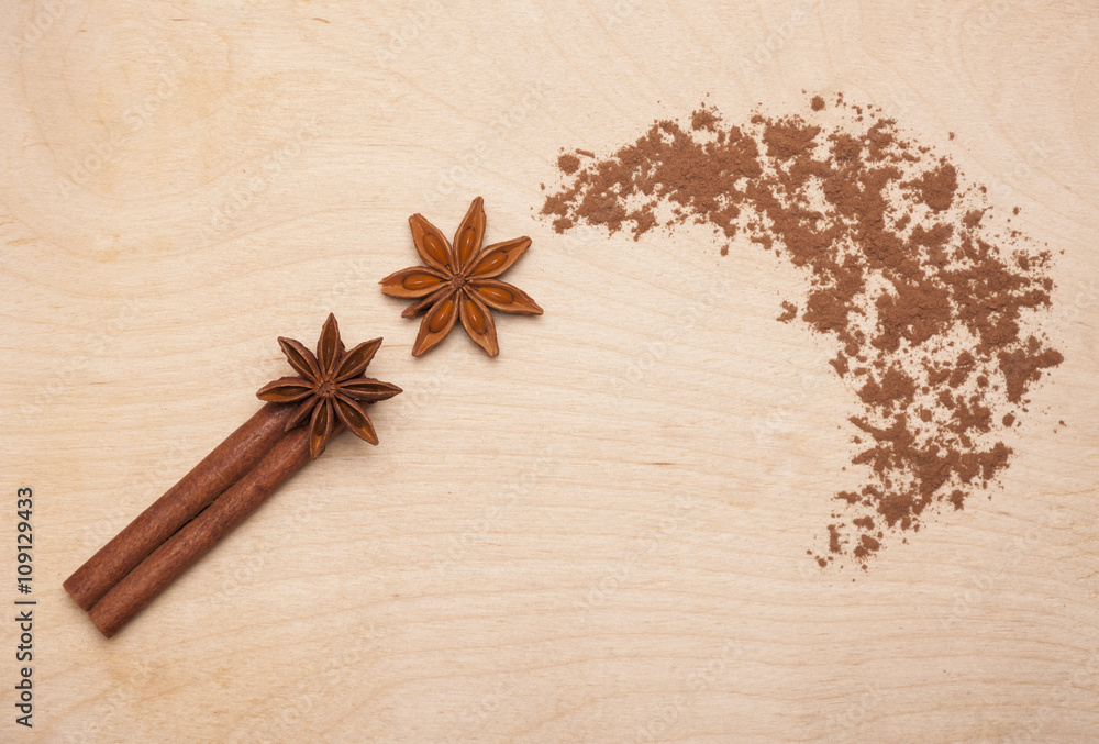 Magic wand made of cinnamon stick, star anise and cocoa powder on wooden background. Magic aromatic spices for healthy and flavored food. Magic wand made of cinnamon stick, star anise and cocoa powder on wooden background. Magic aromatic spices for healthy and flavored food.