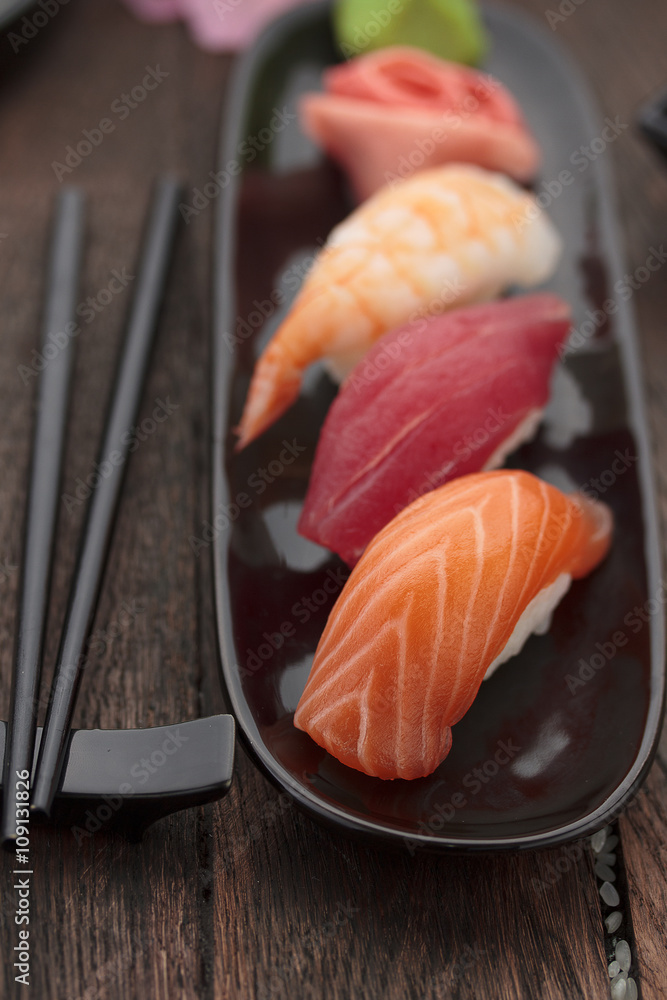 Sushi nigiri set on a black plate over wooden table Sushi nigiri set on a black plate over wooden table