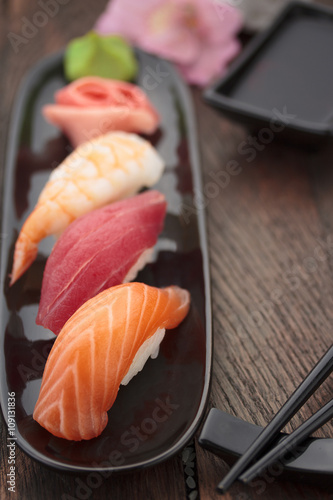 Sushi nigiri set on a black plate over wooden table