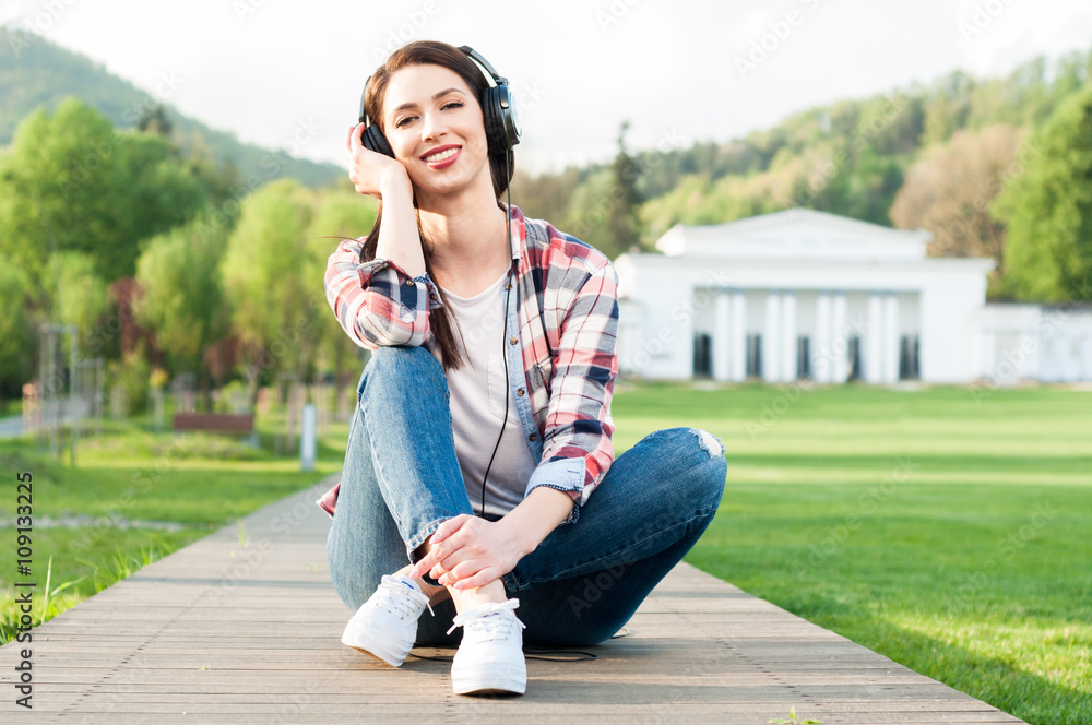 Young beautiful girl with headphones outdoors in the park Young beautiful girl with headphones outdoors in the park