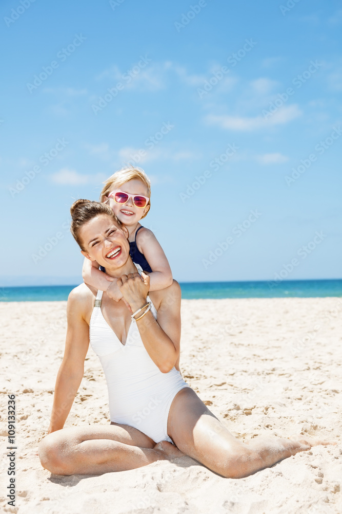happy mother and child in swimsuits at sandy beach on sunny day happy mother and child in swimsuits at sandy beach on sunny day