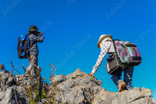 Two women hikers climbing towards the top of mountain.
