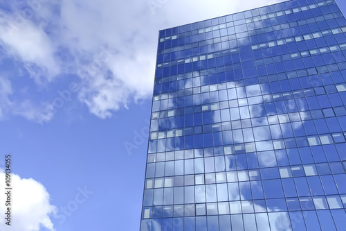 Big blue office building with sky reflection