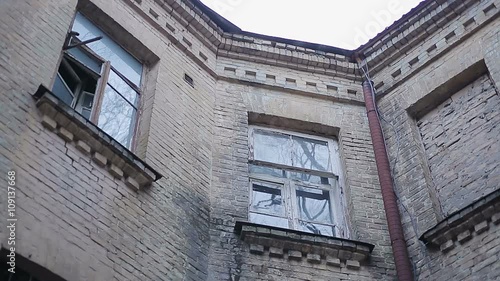 Ancient brick building with old windows and ominous birds sitting on the roof