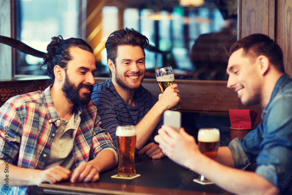 male friends with smartphone drinking beer at bar male friends with smartphone drinking beer at bar