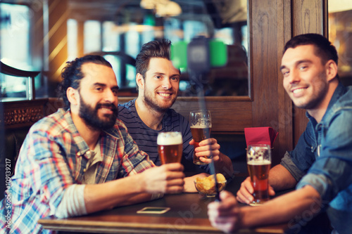 friends taking selfie and drinking beer at bar