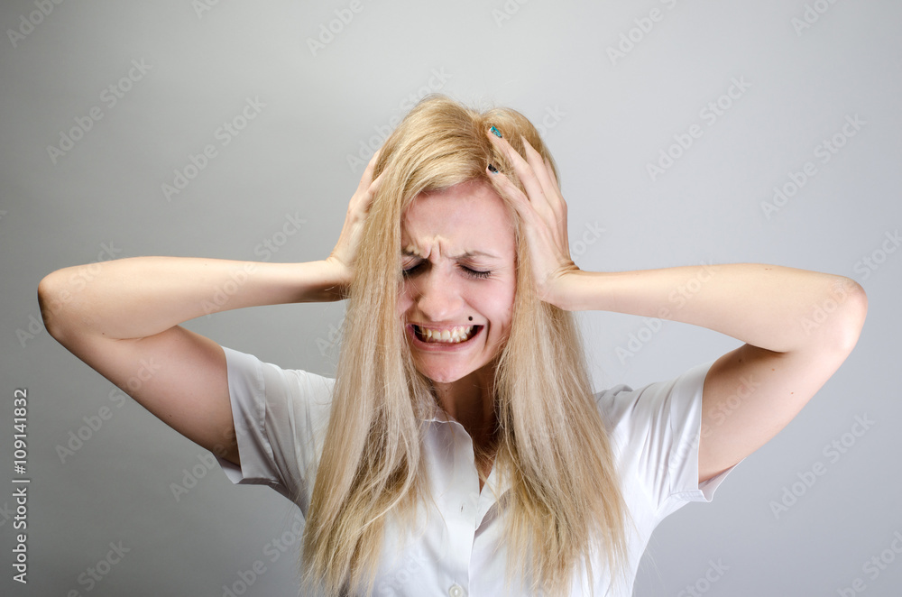 This is too loud! Frustrated young woman in formalwear holding head in hands and keeping eyes closed while standing against grey background This is too loud! Frustrated young woman in formalwear holding head in hands and keeping eyes closed while standing against grey background
