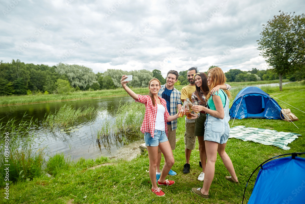 Fototapeta premium happy friends taking selfie by smartphone at camp