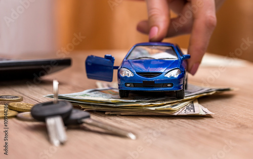 Toy car, keys and money on table