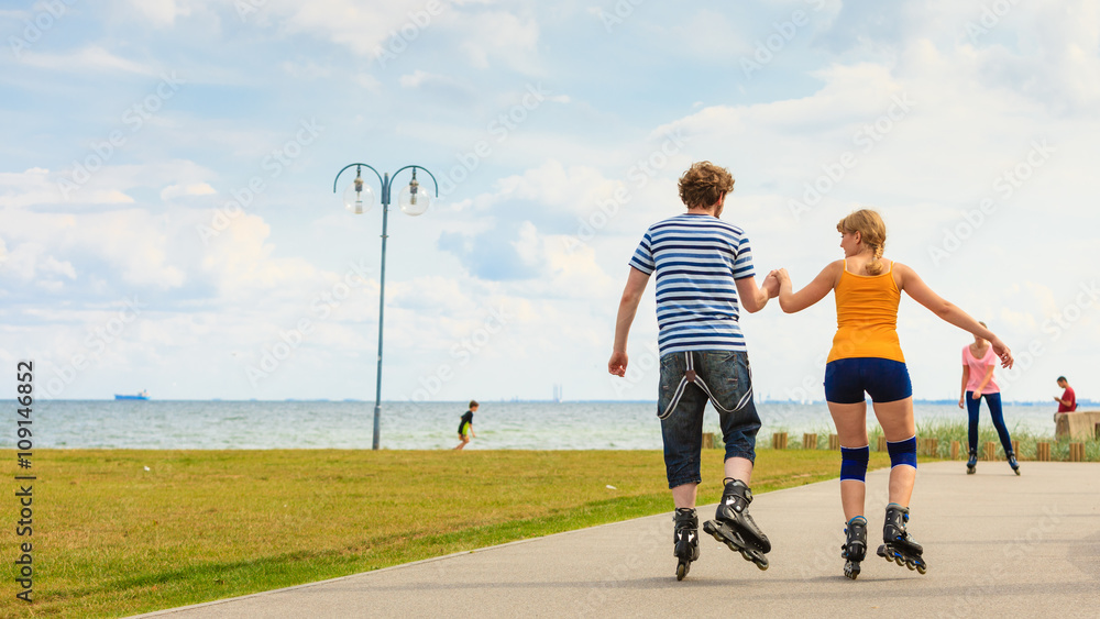 Fototapeta premium Young couple on roller skates riding outdoors