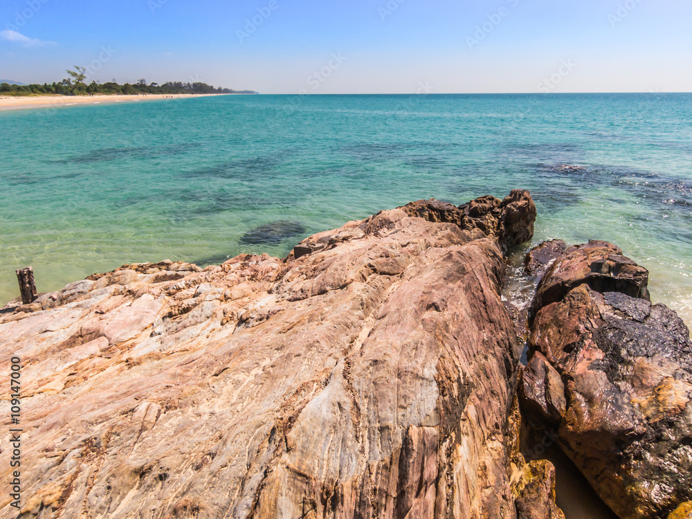 Foreground of rocks with clear blue sea and sky background