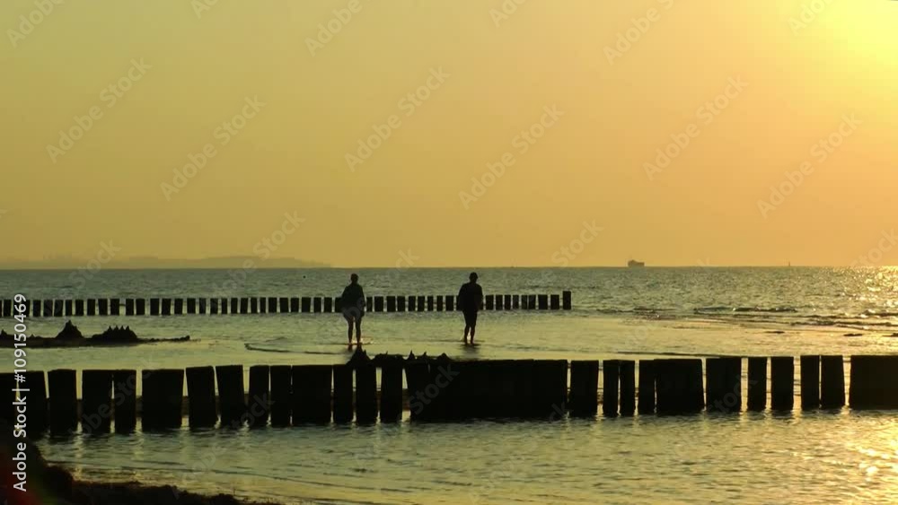 Poel, couple taking a walk in the sea during sunset Poel, couple taking a walk in the sea during sunset